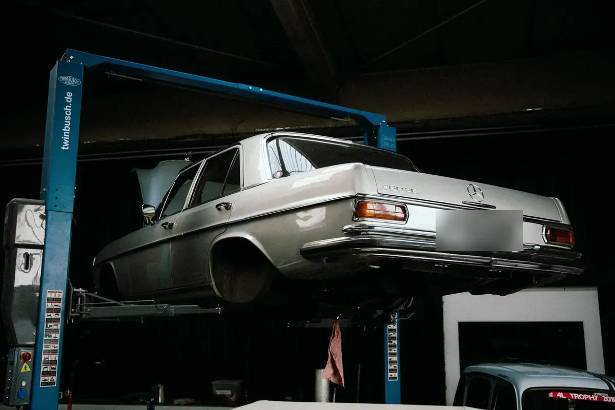 Classic Mercedes-Benz saloon raised on a two-post lift in a workshop