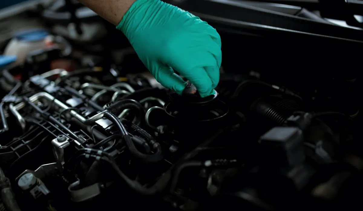 Gloved hand working in the engine bay of a car